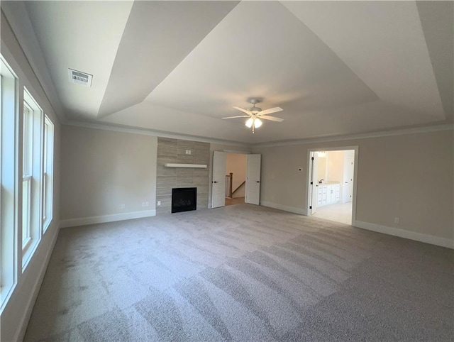 unfurnished living room with a raised ceiling, ceiling fan, carpet flooring, and crown molding