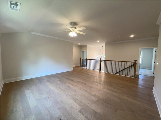 spare room featuring vaulted ceiling, crown molding, wood-type flooring, and ceiling fan with notable chandelier