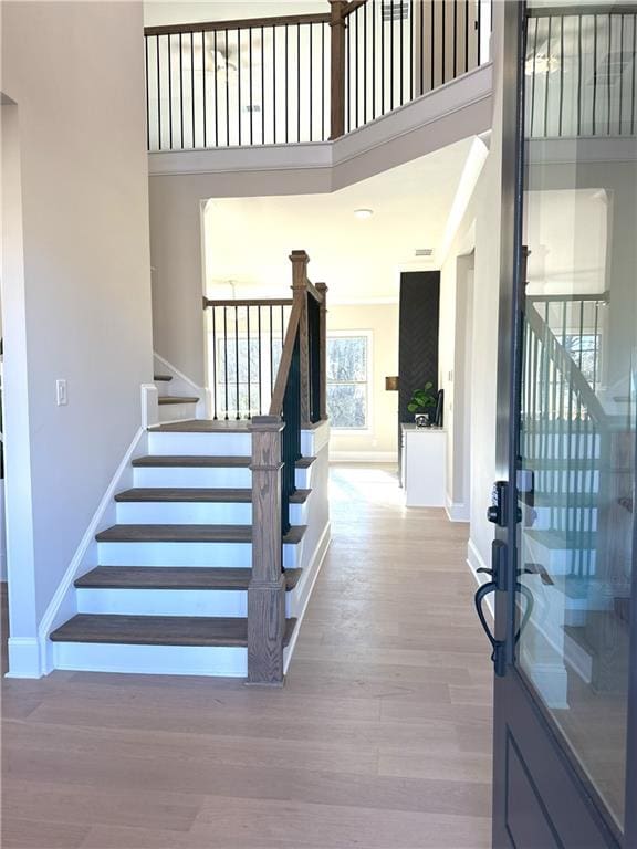 stairway with hardwood / wood-style floors and a high ceiling