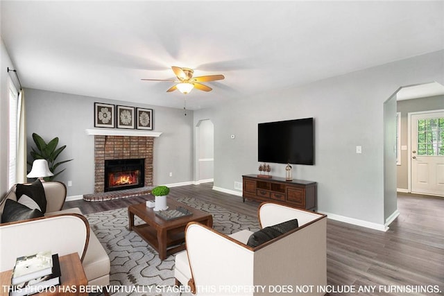 2722 Spring Side Ct, Douglasville, GA 30135 - living area with arched walkways, wood finished floors, a ceiling fan, a fireplace, and baseboards