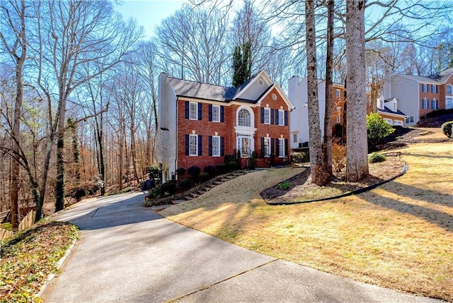 view of front of property featuring brick siding, a chimney, and a front lawn