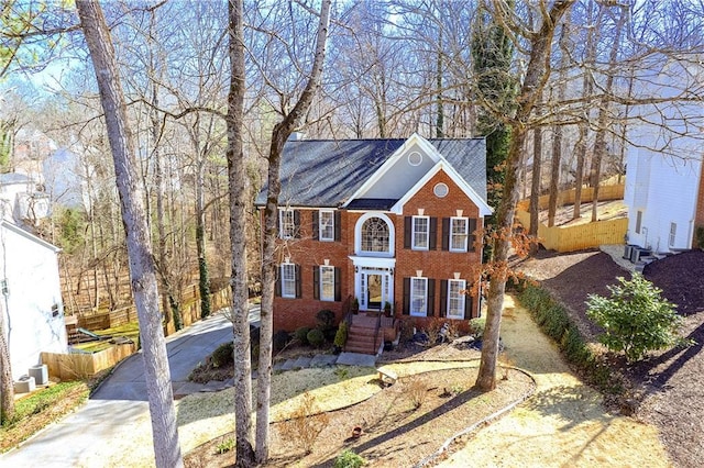 colonial-style house with driveway and brick siding