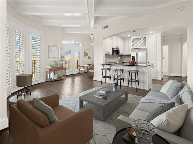 living room with beamed ceiling, ornamental molding, dark hardwood / wood-style flooring, and french doors