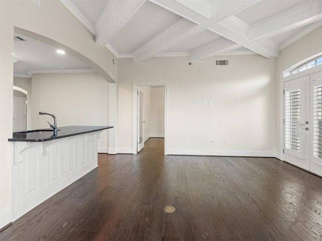 unfurnished living room with dark wood-type flooring, french doors, coffered ceiling, sink, and beamed ceiling