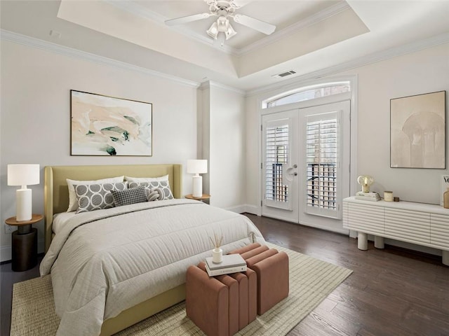 bedroom featuring wood-type flooring, access to exterior, crown molding, and a tray ceiling