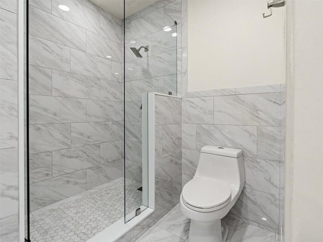 bathroom with a tile shower, tile walls, and toilet