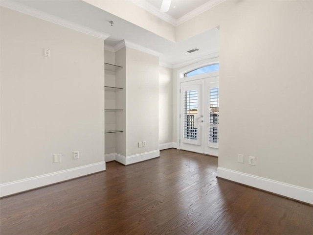 empty room featuring dark hardwood / wood-style flooring, crown molding, french doors, and built in shelves