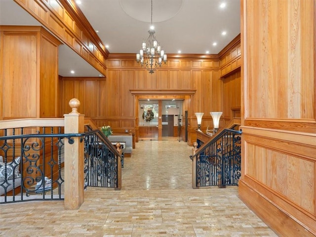 hall with a notable chandelier, wooden walls, and ornamental molding