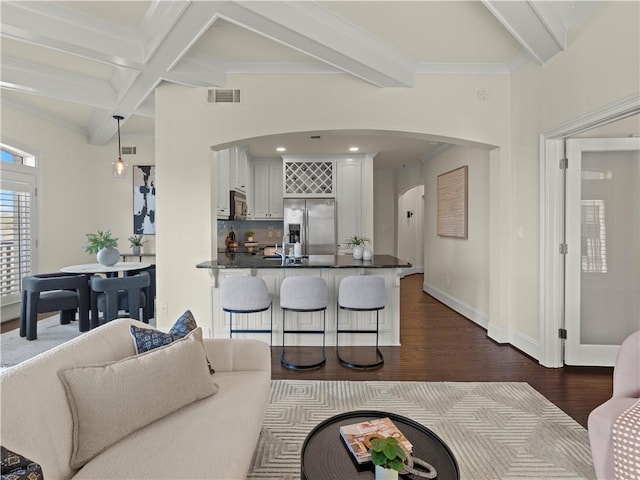 living room with dark hardwood / wood-style flooring, crown molding, and beam ceiling