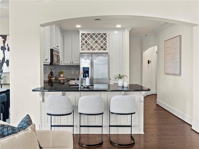 kitchen featuring a breakfast bar, kitchen peninsula, white cabinets, and stainless steel fridge with ice dispenser