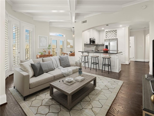 living room with beamed ceiling, ornamental molding, dark wood-type flooring, and french doors