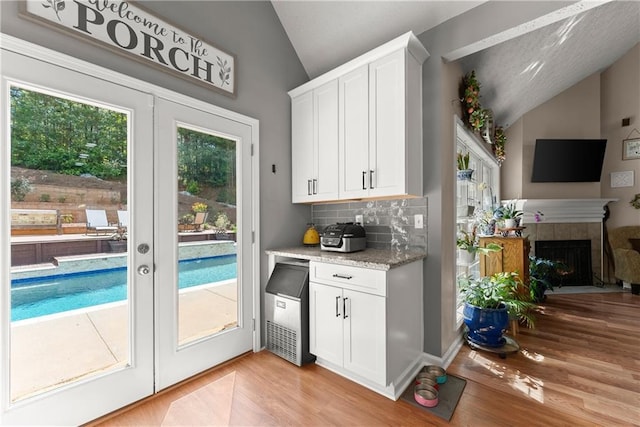69 Maple Leaf Ct, Hoschton, GA 30548 - kitchen featuring vaulted ceiling, light wood-style flooring, decorative backsplash, white cabinets, and open floor plan