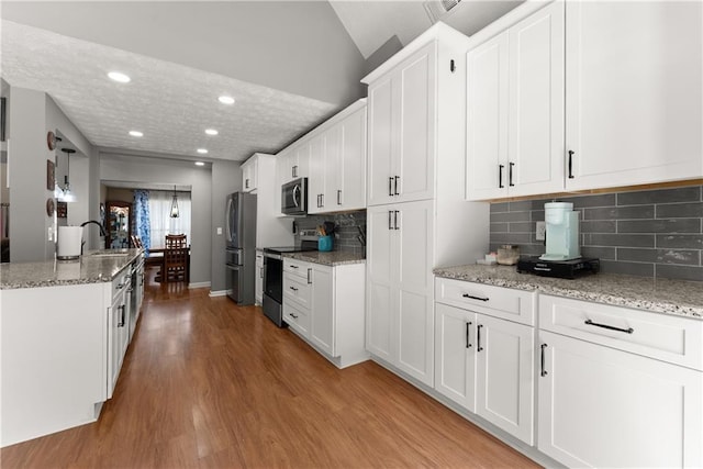 69 Maple Leaf Ct, Hoschton, GA 30548 - kitchen featuring stainless steel appliances, light wood-type flooring, white cabinetry, light stone counters, and recessed lighting