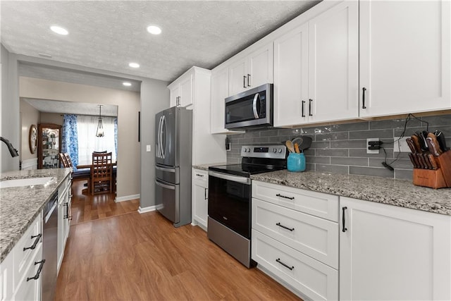 69 Maple Leaf Ct, Hoschton, GA 30548 - kitchen featuring stainless steel appliances, light wood finished floors, white cabinetry, backsplash, and recessed lighting