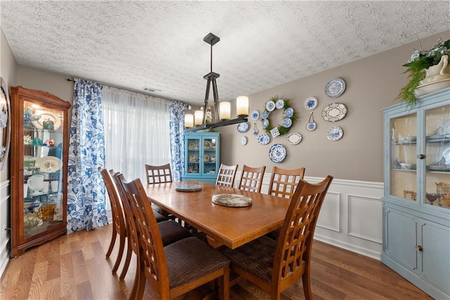 69 Maple Leaf Ct, Hoschton, GA 30548 - dining room with wood finished floors, a textured ceiling, and a wainscoted wall