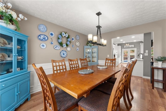 69 Maple Leaf Ct, Hoschton, GA 30548 - dining space featuring a textured ceiling, light wood-style floors, a wainscoted wall, and a chandelier