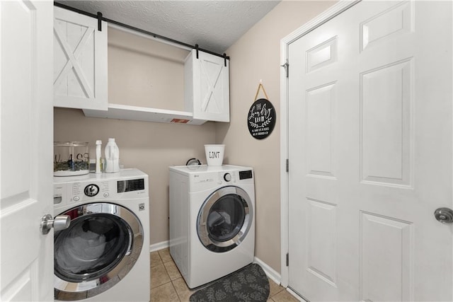 69 Maple Leaf Ct, Hoschton, GA 30548 - laundry area featuring washing machine and dryer, light tile patterned floors, cabinet space, and a textured ceiling