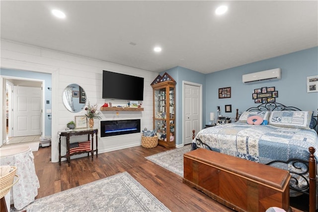 69 Maple Leaf Ct, Hoschton, GA 30548 - bedroom featuring an AC wall unit, wood finished floors, a glass covered fireplace, and recessed lighting