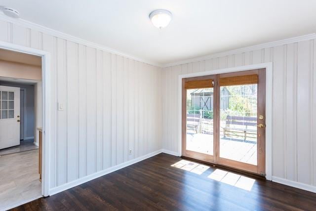 empty room with dark wood finished floors and ornamental molding