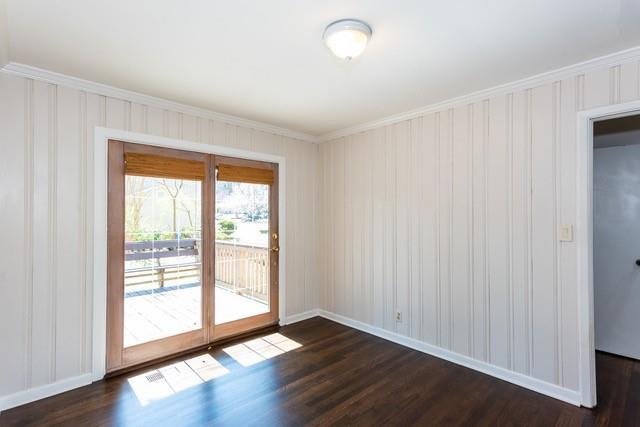 empty room featuring dark wood finished floors, baseboards, and ornamental molding