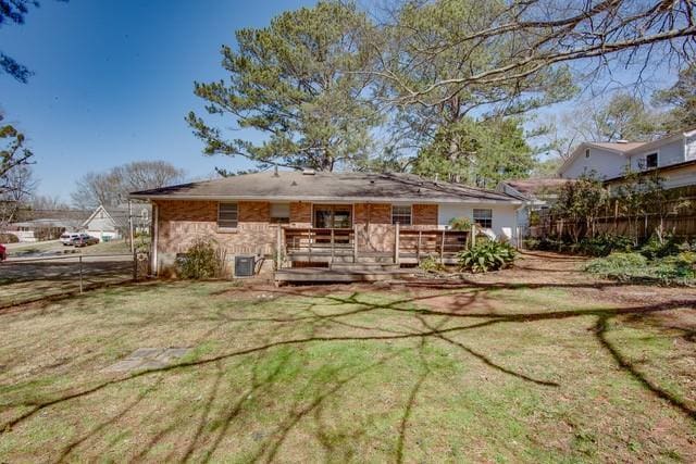 rear view of house with a deck, central air condition unit, a lawn, and fence