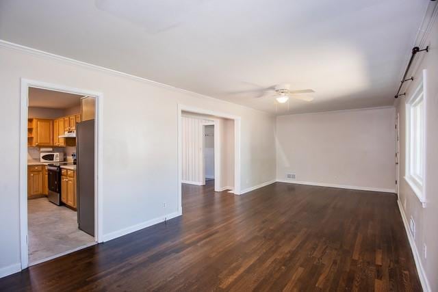 empty room featuring visible vents, a ceiling fan, wood finished floors, crown molding, and baseboards