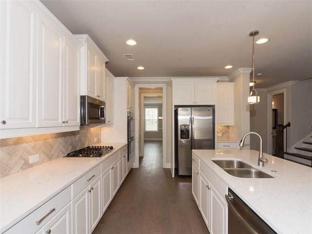 kitchen with appliances with stainless steel finishes, a sink, white cabinets, and pendant lighting