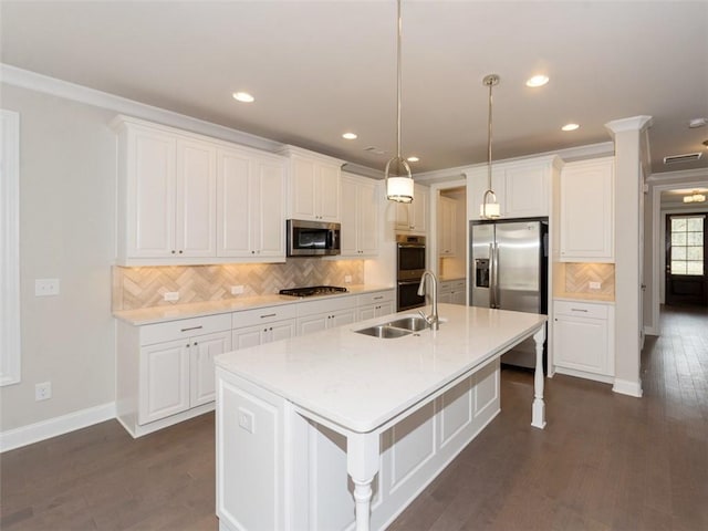 kitchen with a kitchen island with sink, stainless steel appliances, light countertops, white cabinetry, and a sink