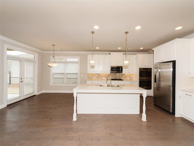 kitchen featuring a center island with sink, stainless steel appliances, light countertops, and decorative light fixtures