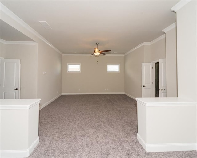 spare room featuring crown molding, baseboards, a ceiling fan, and light colored carpet