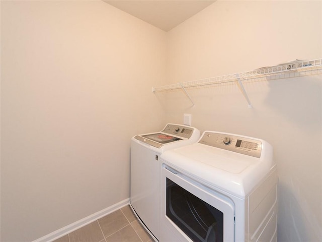 laundry room with laundry area, washing machine and dryer, light tile patterned floors, and baseboards