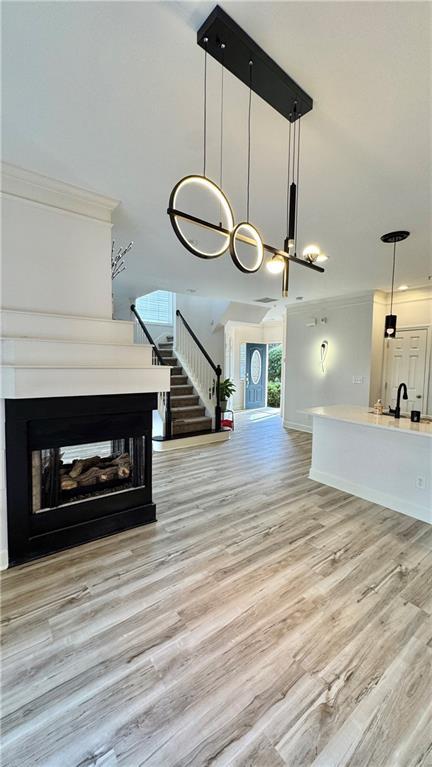 interior space with a multi sided fireplace, light hardwood / wood-style floors, and crown molding