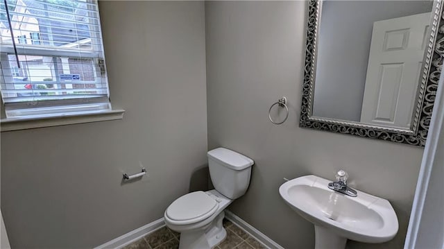 half bathroom featuring a sink, healthy amount of natural light, baseboards, and toilet