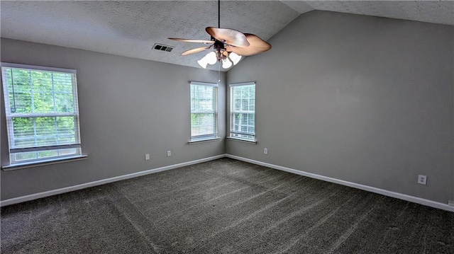 empty room with lofted ceiling, a ceiling fan, baseboards, dark colored carpet, and a textured ceiling
