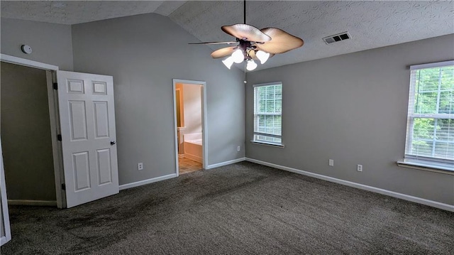 unfurnished bedroom featuring carpet flooring, vaulted ceiling, baseboards, ensuite bath, and a ceiling fan