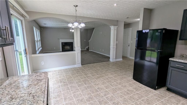 kitchen featuring freestanding refrigerator, arched walkways, a textured ceiling, ornate columns, and a fireplace