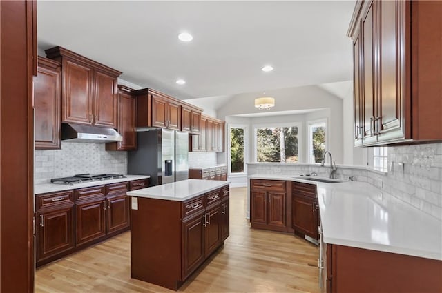 kitchen featuring lofted ceiling, sink, a center island, light wood-type flooring, and appliances with stainless steel finishes