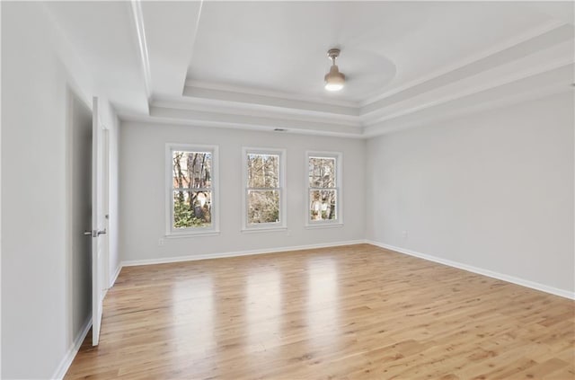 unfurnished room with crown molding, a tray ceiling, and light hardwood / wood-style flooring