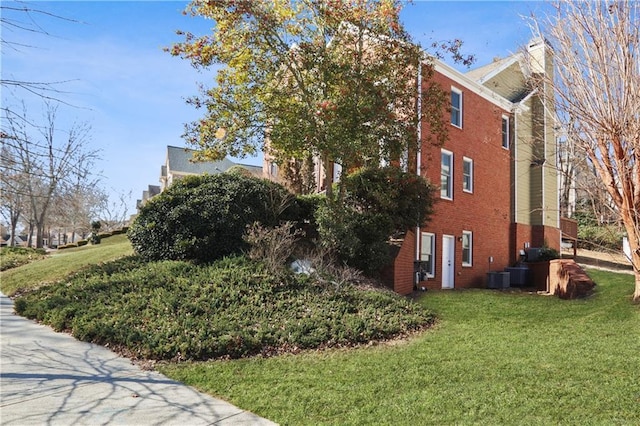 view of side of property with central AC unit and a lawn