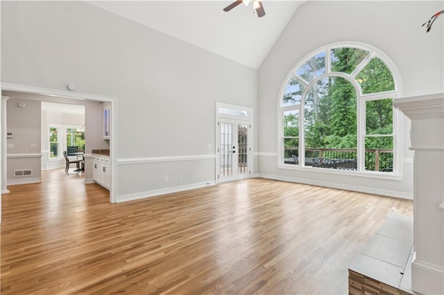unfurnished living room with baseboards, a ceiling fan, light wood-style flooring, and high vaulted ceiling