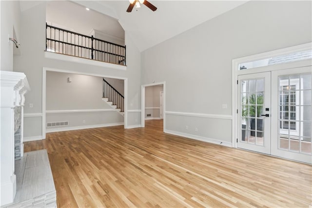 unfurnished living room featuring high vaulted ceiling, a ceiling fan, wood finished floors, visible vents, and stairway