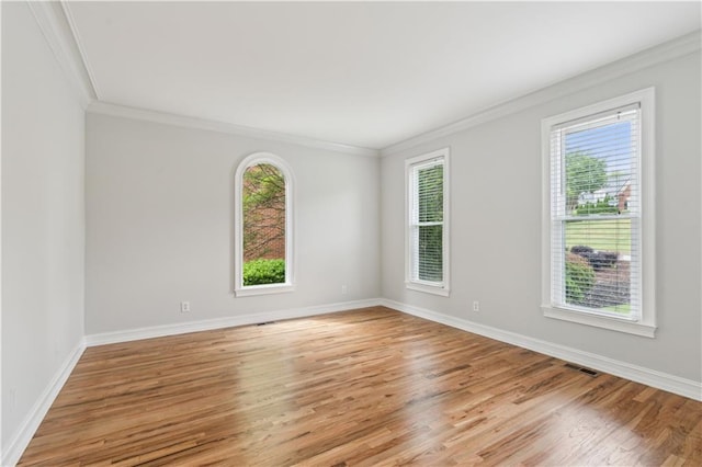 empty room with plenty of natural light, ornamental molding, and light wood-type flooring