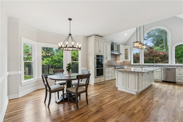kitchen featuring an inviting chandelier, decorative backsplash, wall chimney exhaust hood, and appliances with stainless steel finishes