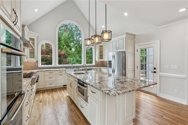 kitchen featuring a sink, vaulted ceiling, stainless steel appliances, and light wood-style flooring
