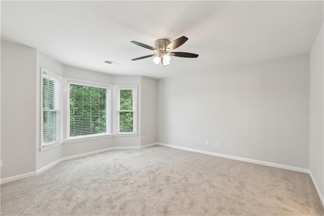 carpeted spare room featuring ceiling fan, visible vents, and baseboards