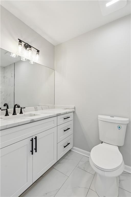 bathroom featuring toilet, baseboards, and marble finish floor