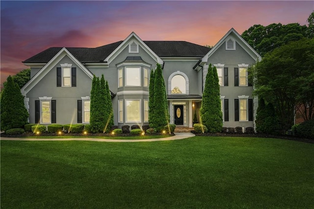 view of front of home with stucco siding and a yard