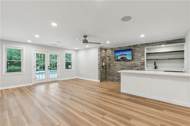 unfurnished living room with recessed lighting, baseboards, a wealth of natural light, and light wood-type flooring
