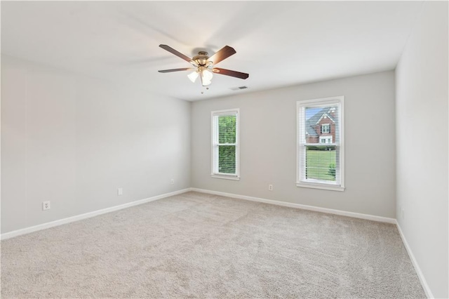 spare room featuring visible vents, baseboards, ceiling fan, and light carpet