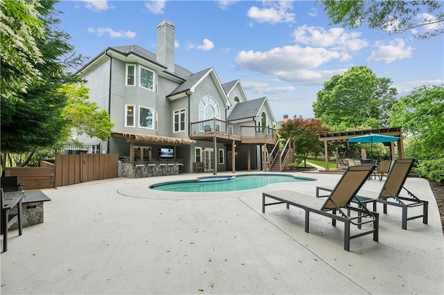 outdoor pool featuring fence, outdoor dry bar, stairs, a wooden deck, and a patio